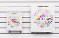 Bolsas de regalo modelo 3072 con diseños Happy Birthday y detalles multicolor para celebraciones. Disponibles en tamaños chica y mediana. Importación directa ROGLUX.